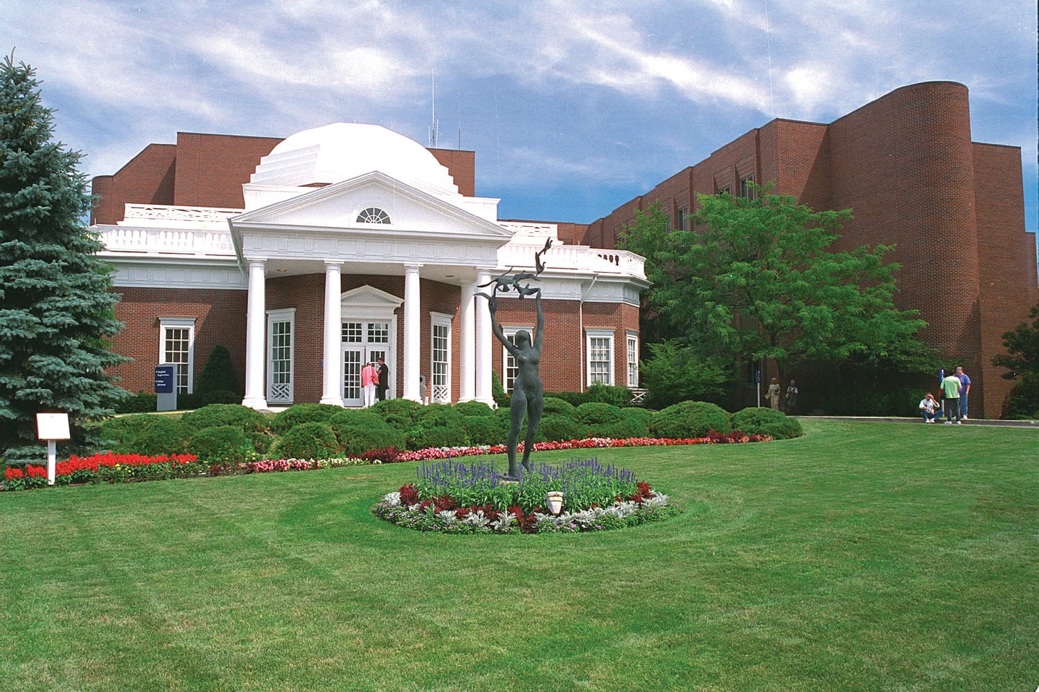 A well-maintained building with a dome and columns surrounded by lush greenery and a landscaped lawn in Oneida County.