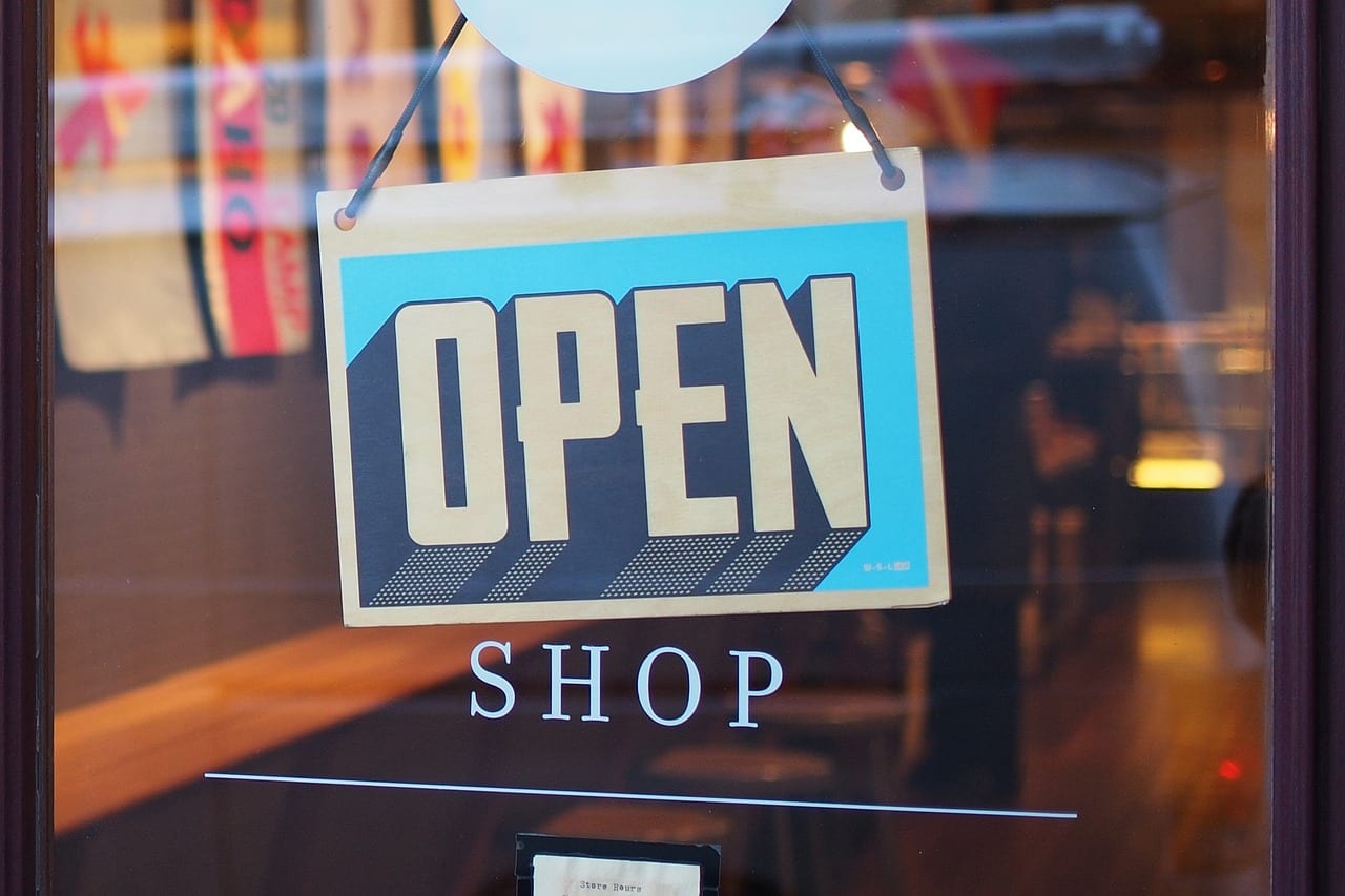 Close-up view of an open sign hanging on a shop window in a town setting.
