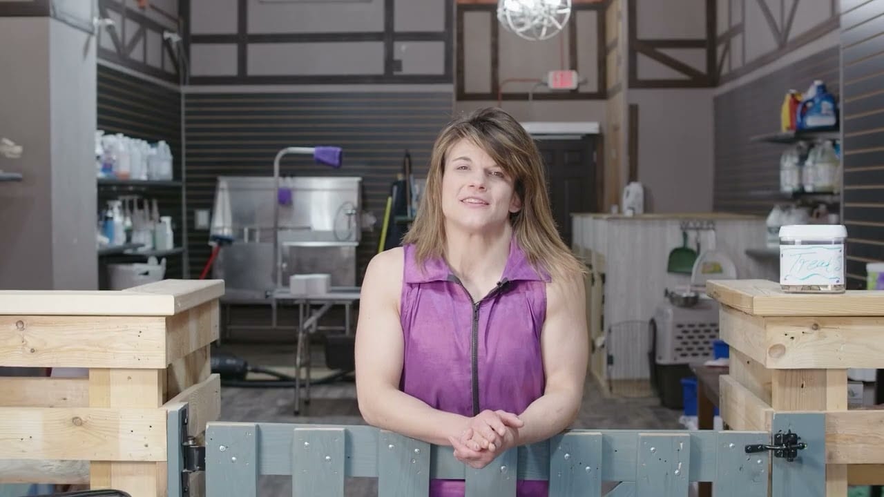 Person in a purple vest standing in a workshop with industrial equipment in the background