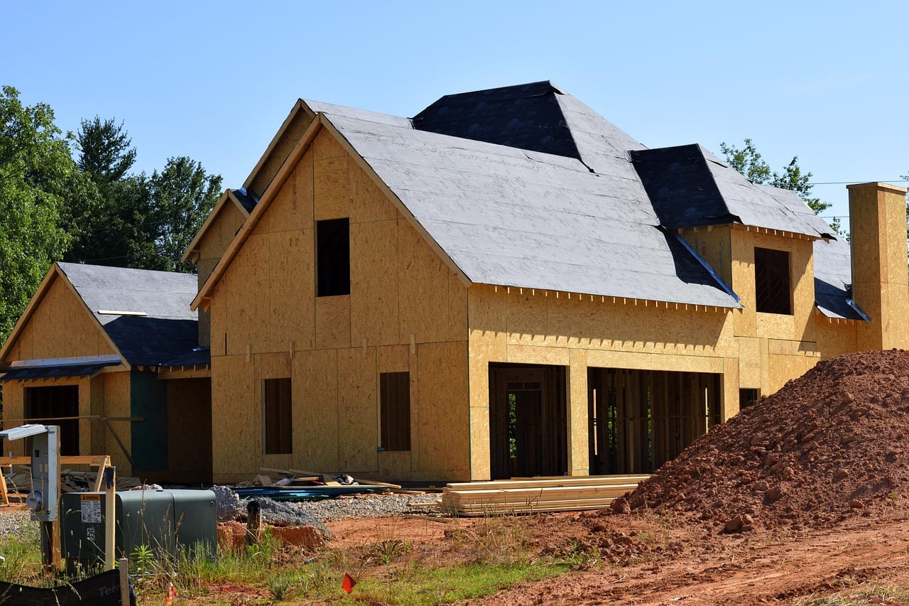 A partially built house with exposed wooden framing and piles of earth at a construction site in Oneida County, Wisconsin.