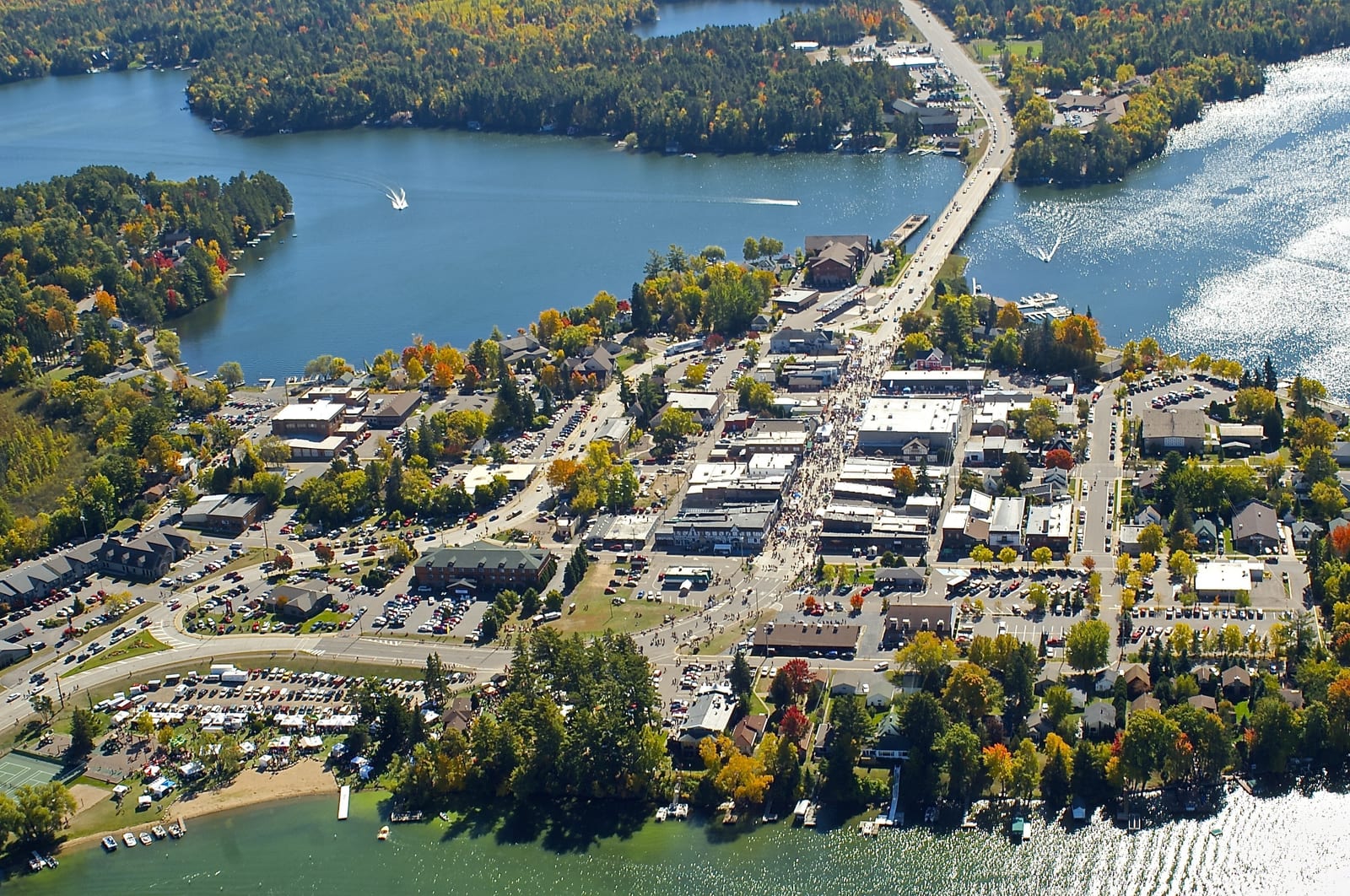 Aerial view of a town with a bridge over a river, surrounded by forests and lakes in Oneida County.