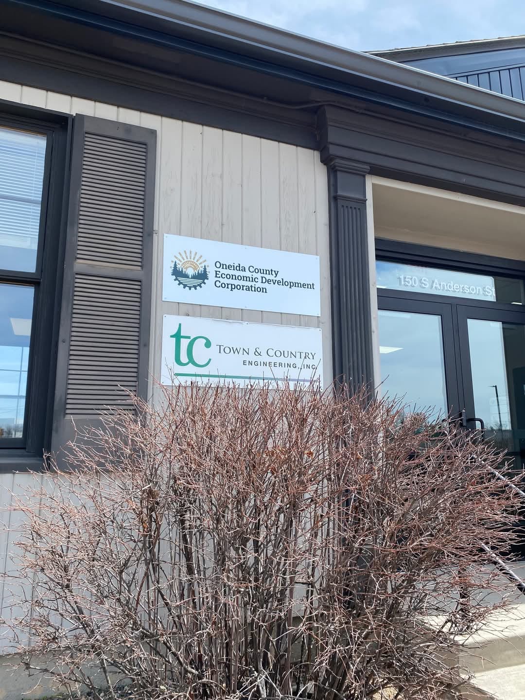 Front view of a building with Oneida County Economic Development Corporation signage above the entrance, next to a leafless shrub