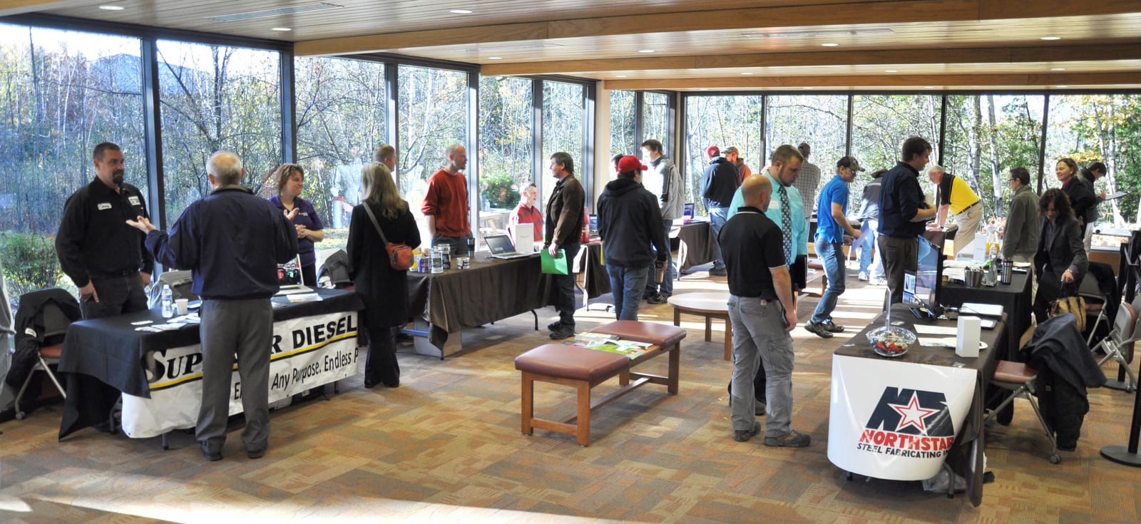 Individuals attending a networking event in a sunlit room with large windows in Oneida County