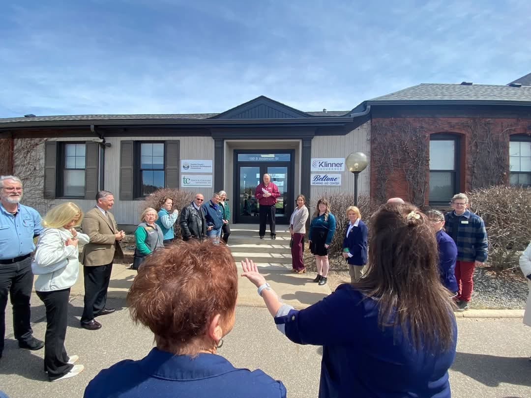 A group of people stands in a semicircle in front of a building during a ribbon-cutting ceremony, celebrating economic development and community partnerships in Oneida County, WI.