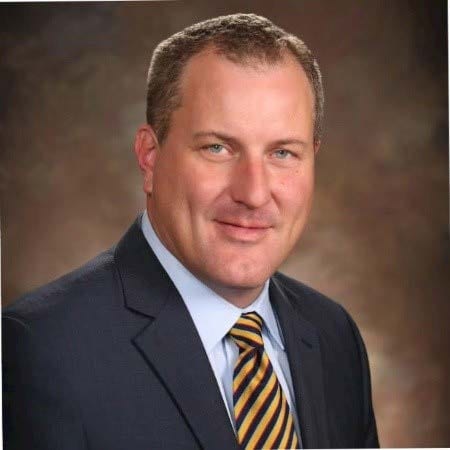 Portrait of a business executive in a dark suit and striped tie against a brown background