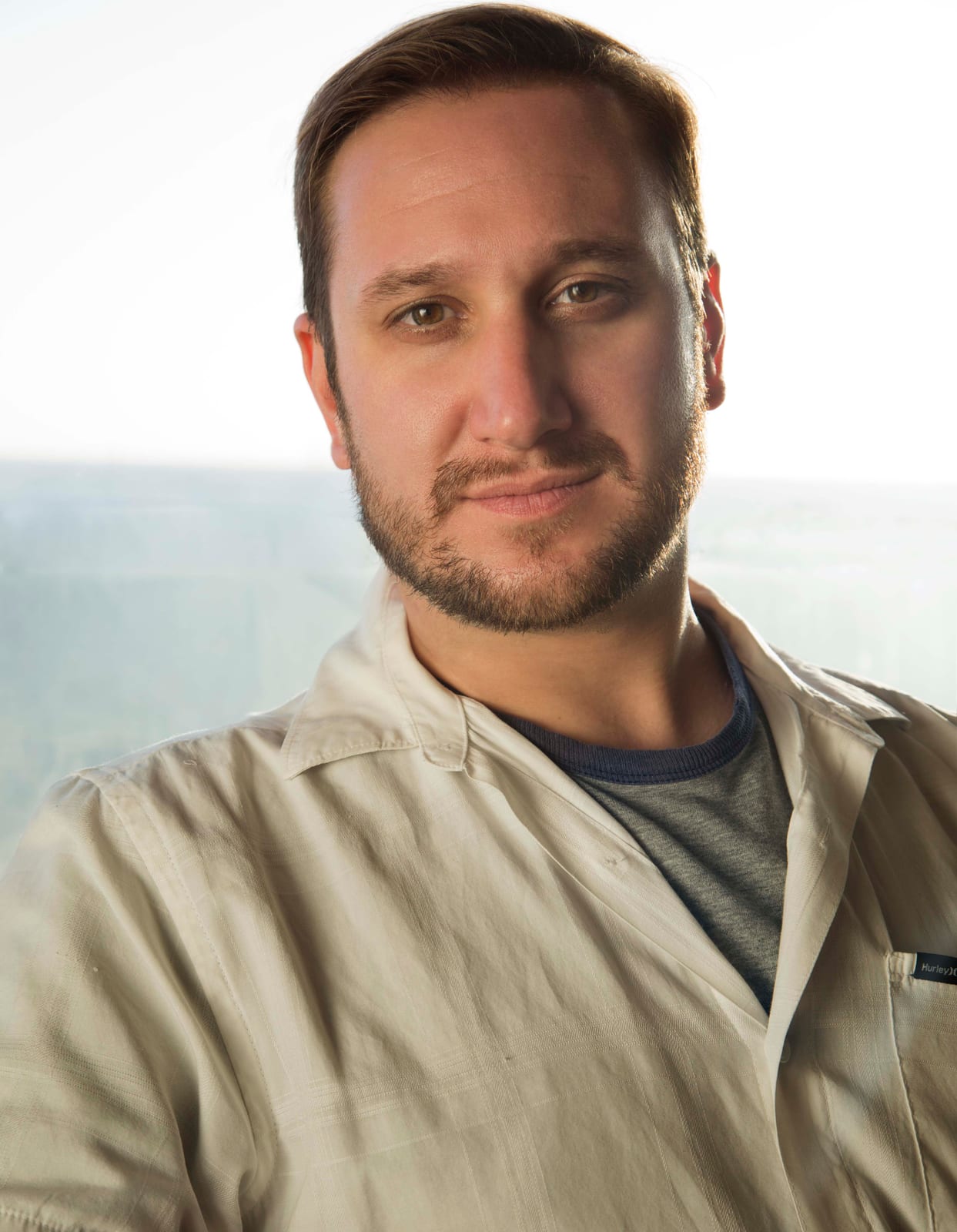 Portrait of a man in a white shirt standing indoors with a soft blurred background