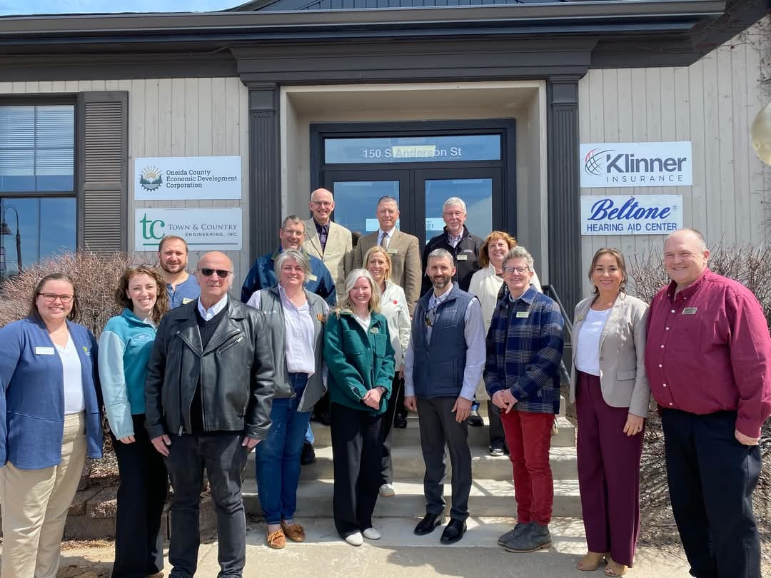 Group of people standing in front of the Oneida County Economic Development Corporation office building for a ribbon cutting ceremony.