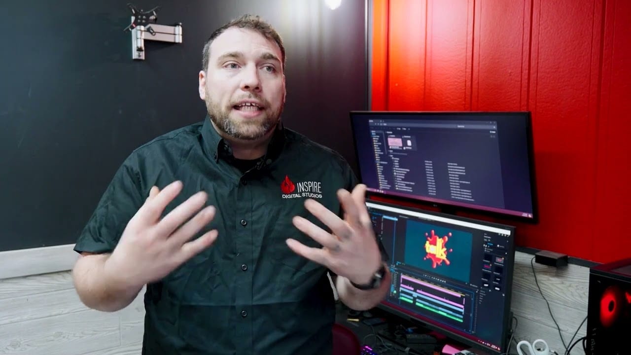 Man in a professional setting with dual monitors, discussing in front of computers