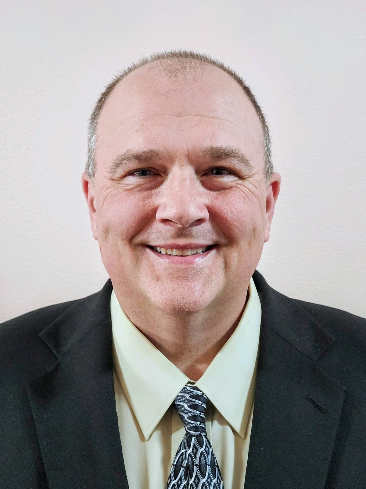 Smiling individual wearing a suit against a light background